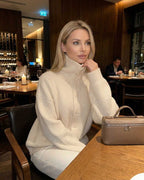 Model wearing the Selene Sweater by Lauven, a ribbed turtleneck button-up women’s sweater, in a cozy restaurant setting.