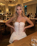 Serena Mini Dress by Lauven, showcasing a model in a strapless ivory corset dress with flared skirt.