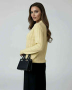 Model wearing the Soleil Sweater by Lauven, a women's yellow knit sweater with long sleeves and a stylish look.
