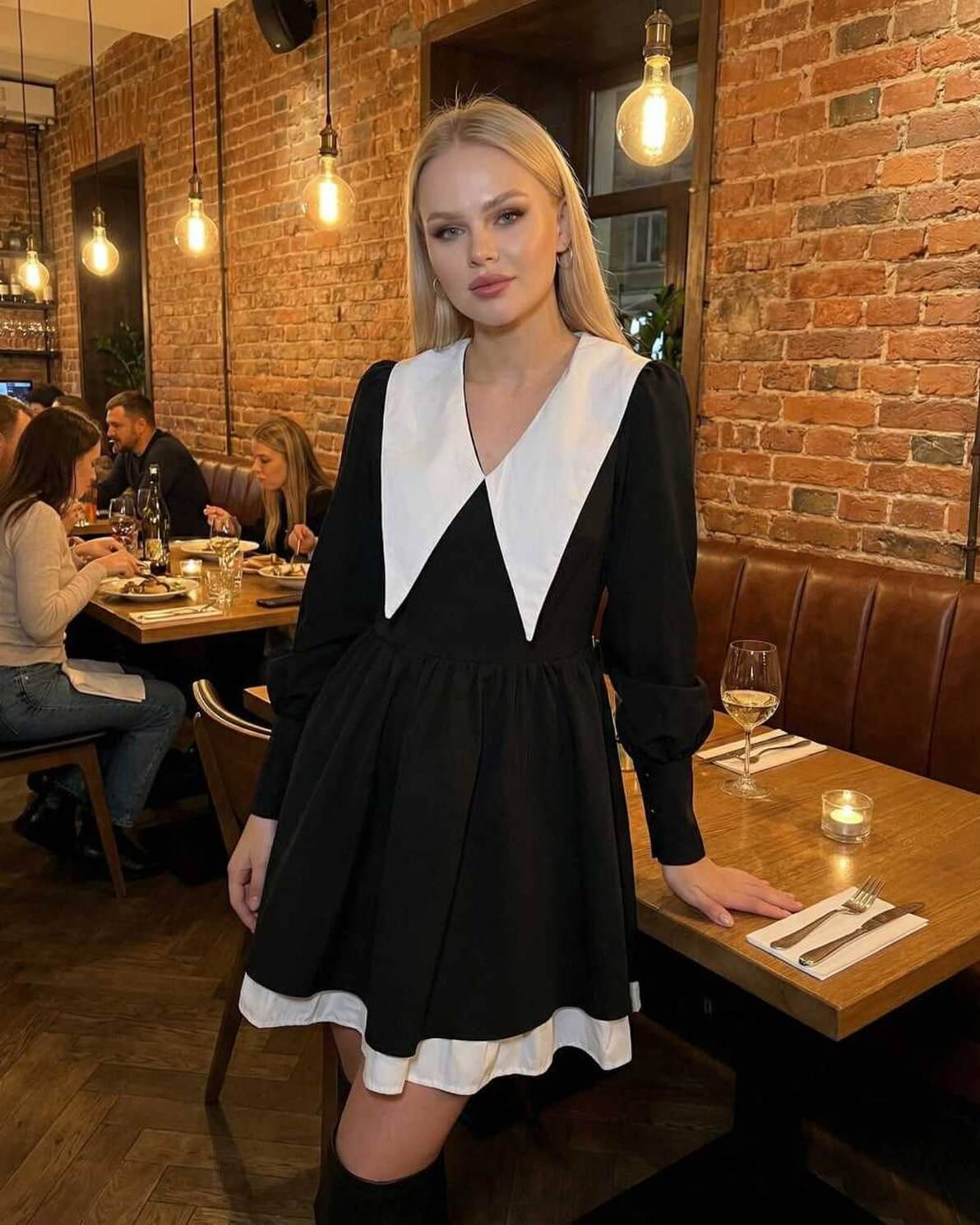 Vesper Mini Dress by Lauven featuring black and white patchwork design with lapel collar, worn in a cozy restaurant setting.