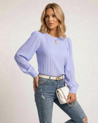Luna Blouse by Lauven in soft lavender with pleated long sleeves, styled with jeans and a white handbag.
