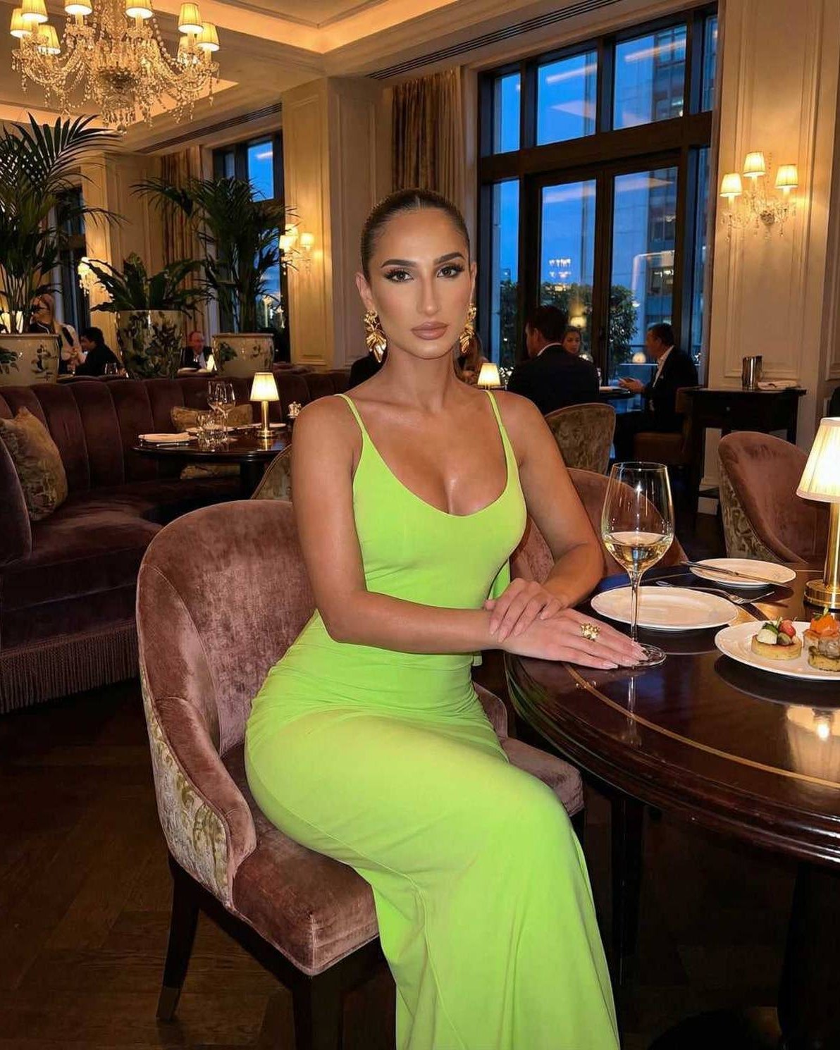 Lauven Luna Maxi Dress in vibrant lime green worn at a stylish restaurant, highlighting sleek sleeveless design.