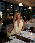 Lauven Luna Mini Dress showcased in an elegant restaurant setting, highlighting the soft draped V-neckline and umbrella skirt.