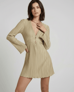 Elegant model wearing Luna Mini Dress by Lauven in light beige with pleated texture and deep V-neckline.