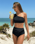 Model enjoying a drink in the Lauven Midnight Two-Piece Swimsuit, featuring an asymmetric design and black color.