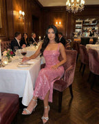 Lauven Mira Midi Dress in pink sequined elegance worn at a dining table, showcasing backless design and chic silhouette.