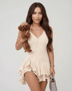 Lauven Monaco Mini Dress in beige with halter neck, layered ruffle hem, and a model holding a dog.