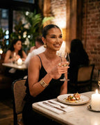 Woman enjoying a drink in a Nocturne Maxi Dress by Lauven at a stylish restaurant.