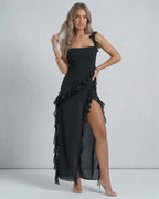 Lauven Nocturne Maxi Dress in black, featuring sheer ruffles, thigh-high slit, and elegant silhouette.