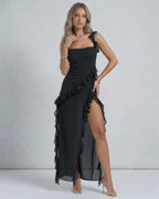 Lauven Nocturne Maxi Dress features a sheer ruffled design, asymmetrical hem, and thigh-high side slit.