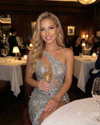 Nova Mini Dress by Lauven worn by a woman in a restaurant, showcasing silver sequins and a stylish one-shoulder design.