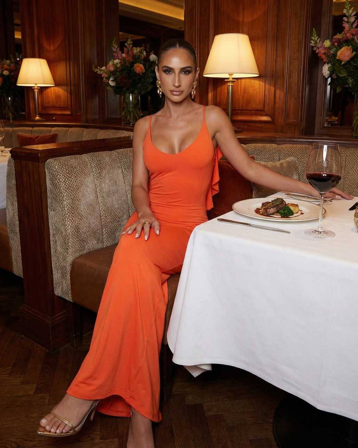 Orion Maxi Dress by Lauven, sleek orange sleeveless silhouette worn at a restaurant table.