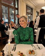Orion Mini Dress by Lauven in emerald green sequins worn at an elegant dinner table setting.