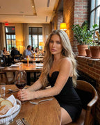 Stylish woman wearing Eestella Mini Dress by Lauven with sheer embellished sleeves in a chic restaurant setting.