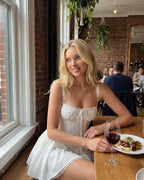 Elysia Mini Dress by Lauven worn by a woman in a restaurant setting, showcasing corset bodice and flared skirt.