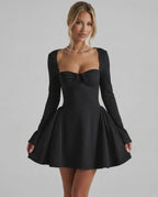 Noir Mini Dress showcasing a flattering fit-and-flare silhouette, long sleeves, and ruched bow detail by Lauven.