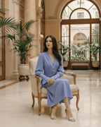 Model in a blue Selene Midi Dress, featuring a V-neck and lantern sleeves, showcasing elegance in a refined setting.