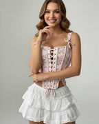 Seraphina Corset Top by Lauven featuring a pink floral design and lace-up front, paired with a ruffled white skirt.