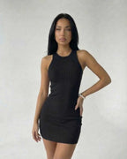 Model wearing the Sienna Mini Dress by Lauven, a sleek black ribbed knit sleeveless bodycon mini dress.