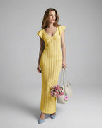 Lauven Solara Maxi Dress in yellow lace with V-neck and ruffle sleeves, paired with a floral handbag.