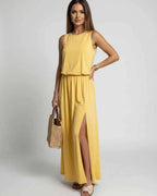 Solara Maxi Dress featuring a yellow sleeveless silhouette with side slit, styled with a bag, by Lauven for a modern look.
