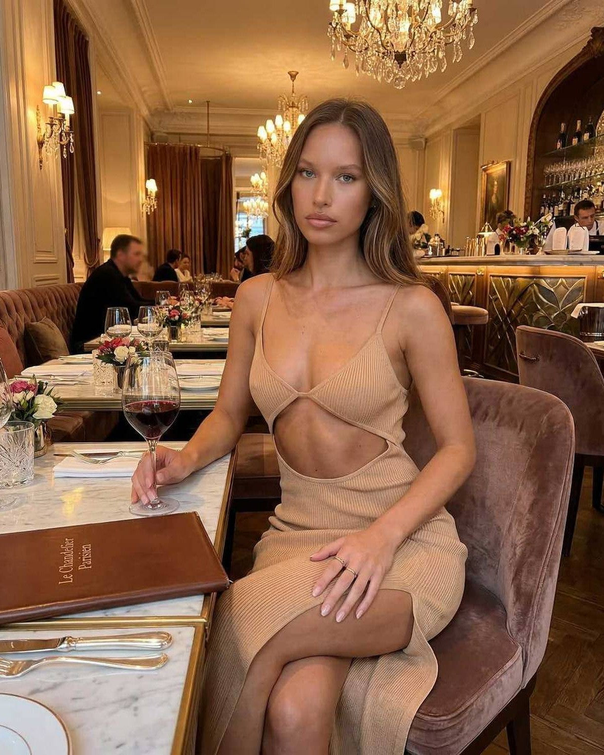 Solara Midi Dress by Lauven - Elegant cut-out spaghetti strap dress in nude worn at a classy restaurant setting.