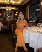 Soleil Maxi Dress by Lauven in vibrant orange worn at a restaurant, highlighting its sexy club-ready style.
