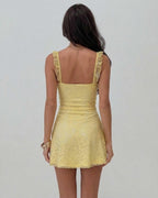 Back view of the Sunny Mini Dress by Lauven featuring elegant lace detailing in soft yellow.