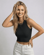 Model wearing the Valencia Top by Lauven, a ribbed knit cropped sleeveless black top, styled with white jeans.