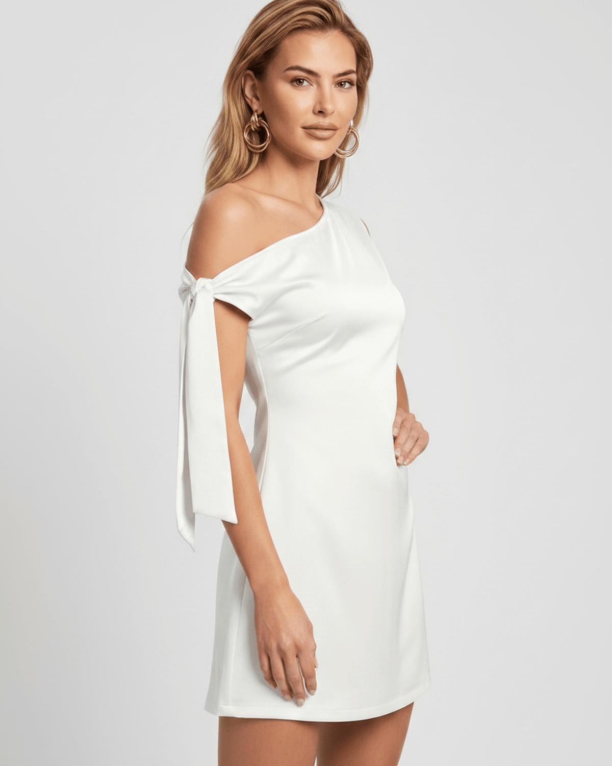 Veloura Mini Dress in white with asymmetric neckline and bow tie sleeves, soft satin finish by Lauven.