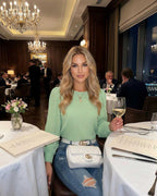 Verde Blouse by Lauven worn by a woman in a restaurant, featuring fresh green pleated long sleeves and stylish denim.