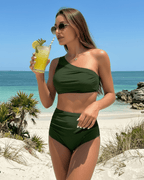 Woman in a green Verde Two-Piece Swimsuit by Lauven, enjoying a drink on a beach with palm trees.